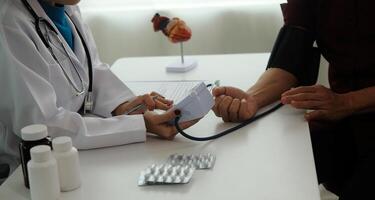 Doctor using sphygmomanometer with stethoscope checking blood pressure to a patient in the hospital. photo