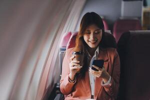 Attractive Asian female passenger of airplane sitting in comfortable seat while working laptop and tablet with mock up area using wireless connection. Travel in style, work with grace. photo