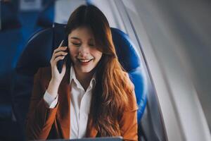 Young Asian executive excels in first class, multitasking with digital tablet, laptop and smartphone. Travel in style, work with grace. photo