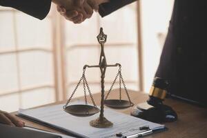 Lawyer shaking hands with a client making about documents, contracts, agreements, cooperation agreements with a female client at the lawyer's desk and a hammer at the table. photo