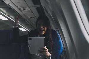 Young Asian executive excels in first class, multitasking with digital tablet, laptop and smartphone. Travel in style, work with grace. photo