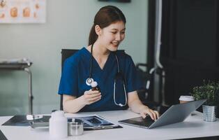 Female doctor writing in a notebook and holding a medicine bottle works at a computer while there were many medicine bottles on the table while sitting at a work desk photo