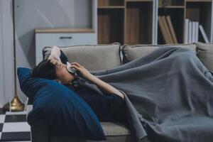 A woman with a cold with pills is treated at home chooses which drugs to take and self-medicates, checks the expiration date while sitting on the couch at home photo