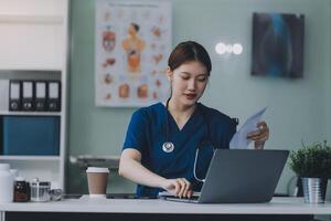 Female doctor writing in a notebook and holding a medicine bottle works at a computer while there were many medicine bottles on the table while sitting at a work desk photo