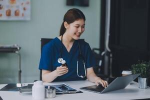 Female doctor writing in a notebook and holding a medicine bottle works at a computer while there were many medicine bottles on the table while sitting at a work desk photo