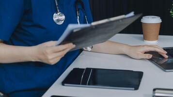 Female doctor writing in a notebook and holding a medicine bottle works at a computer while there were many medicine bottles on the table while sitting at a work desk photo