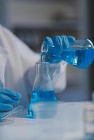 Group of dedicated scientist conduct chemical experiment in medical laboratory, carefully drop precise amount of liquid from pipette into test tube for vaccine drug or antibiotic development. Neoteric photo