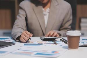 Business woman using calculator and writing make note with calculate. Woman working at office with laptop and documents on his desk photo