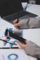Business woman using calculator and writing make note with calculate. Woman working at office with laptop and documents on his desk photo
