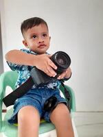 a toddler boy holding a DSLR camera photo