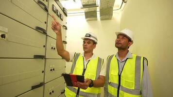 Engineer men in safety gear are looking at a tablet. One of them is wearing a yellow vest video