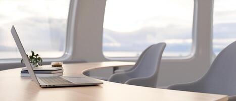 A side view of a laptop computer on a wooden curved table in a minimalist bright office. photo
