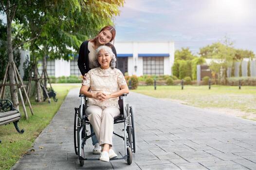 un feliz, positivo retirado asiático abuela en un silla de ruedas es en un parque con su encantador nieta. foto