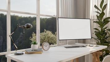 A minimalist white computer desk against the window in a minimal room features a computer mockup. photo