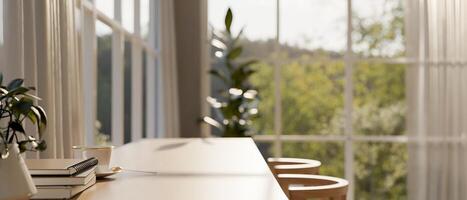 A wooden table in a Scandinavian room with sunlight streaming through an amazing large window. photo