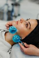 The master gives the client a relaxing facial massage using cold cryo spheres. photo