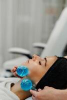 The master gives the client a relaxing facial massage using cold cryo spheres. photo
