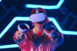 Young female gamer in pink is playing virtual reality games. VR headset and controllers. photo