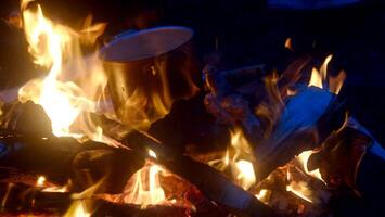 Outdoor campfire. Campfire for cooking food on a camping trip. Fire on a black background. Vertical photo
