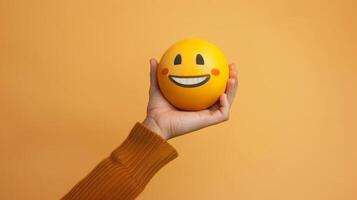 Smiling Emoji Held in Hand Against a Warm Background photo