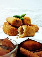 Traditional Indonesian snack Sosis Solo from Central Java, made from savory flour dough and filled with delicious minced chicken or beef then fried. More delicious if eaten with green cayenne pepper photo