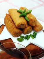 Traditional Indonesian snack Sosis Solo from Central Java, made from savory flour dough and filled with delicious minced chicken or beef then fried. More delicious if eaten with green cayenne pepper photo