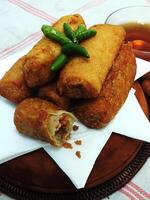 Traditional Indonesian snack Sosis Solo from Central Java, made from savory flour dough and filled with delicious minced chicken or beef then fried. More delicious if eaten with green cayenne pepper photo