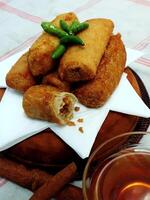 Traditional Indonesian snack Sosis Solo from Central Java, made from savory flour dough and filled with delicious minced chicken or beef then fried. More delicious if eaten with green cayenne pepper photo