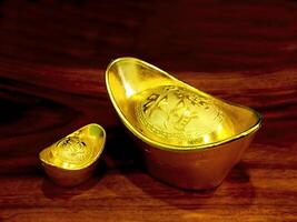 Chinese gold ingots on wooden table background. Chinese New Year concept image for good luck, wealth and prosperity. photo