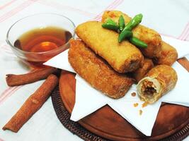 Traditional Indonesian snack Sosis Solo from Central Java, made from savory flour dough and filled with delicious minced chicken or beef then fried. More delicious if eaten with green cayenne pepper photo