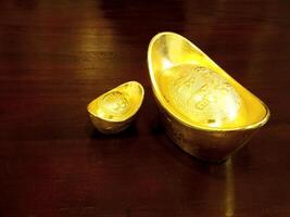 Chinese gold ingots on wooden table background. Chinese New Year concept image for good luck, wealth and prosperity. photo