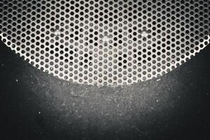 closeup of a surface with a pattern of circular holes in a metal grille or perforated sheet photo