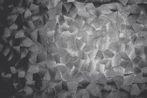 Monochromatic, textured pattern on glass with overlapping, undulating lines that create an illusion of three-dimensional waves on a flat surface photo