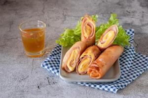 Deep fried spring rolls with ham and cheese on table as appetizer for big meal photo