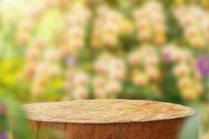 Empty old tree stump table top with blur orchid garden background for product display photo
