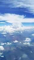 Vertical view of a blue sky with white fluffy cumulus clouds from an airplane window photo