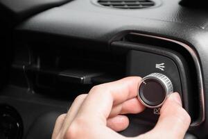 Hand turning the air conditioning control button inside the car for changing the air conditioning mode in a luxury and modern car in year 2024. photo