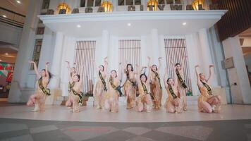 A group of dancers in sparkling gold costumes perform a synchronized routine in an elegant hall with white columns video