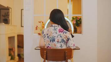 posterior ver de un mujer sentado a un vendaje mesa con un espejo en un acogedor habitación. video