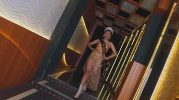 A dynamic group of female dancers performing in golden costumes with a modern indoor setting as a backdrop video