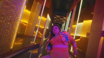 Blurred motion of a woman walking through a neon-lit corridor, creating a dynamic and colorful urban night scene. video