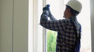 Indian worker with screwdriver installing and checking window in the house video