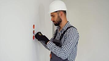 Electrician with pliers installing or repairing power socket in room video