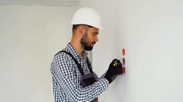 Electrician in uniform using pliers while replacing a socket in apartment after renovation work video