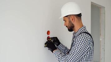 Electrician with pliers installing or repairing power socket in room video