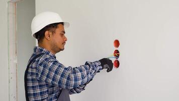 Indian electrician with pliers installing or repairing power socket in room video