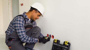 Indian electrician at work, installation of sockets and switches. Professional in overalls with an electrician's tool video
