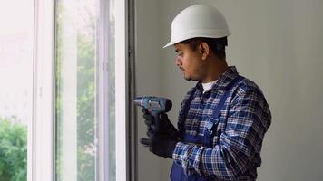 Indian worker with screwdriver installing and checking window in the house video