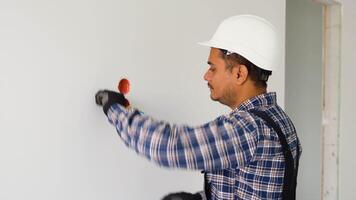 Indian electrician in uniform using pliers while replacing a socket in apartment after renovation work video