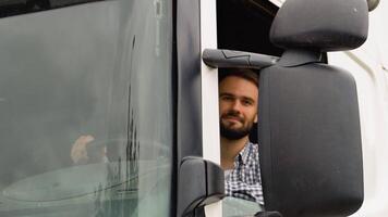 A driver sitting inside the semi-truck while looking at camera through the open window video